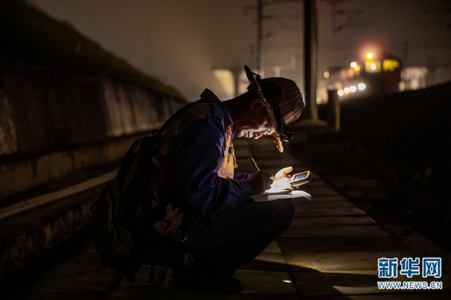借着头灯的微光，一名铁路职工认真记录精调作业的相关数据（摄于11月19日）。新华网发（何俊云 摄）.jpg