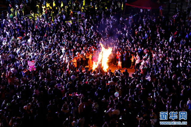 火把节现场，人们围绕巨型火把载歌载舞（资料图）。新华网发（龙俊 摄）