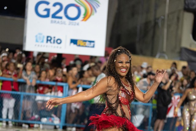 1月21日，在巴西里约热内卢桑巴大道举行的狂欢节彩排上，演员在一处带有“G20”标识的海报前表演。（新华社记者 王天聪摄）