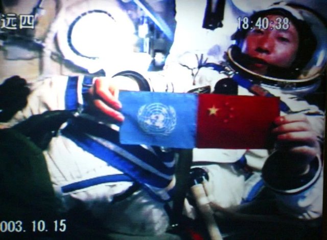 北京时间2003年10月15日18时40分，中国第一位航天员杨利伟从太空向世界各国人民问好，并在舱内并列展示了五星红旗和联合国旗（摄于北京航天指挥控制中心大屏幕）。新华社记者赵建伟摄