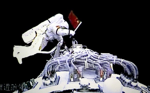 2008年9月27日，执行神舟七号载人航天飞行出舱活动任务的航天员翟志刚出舱后挥动中国国旗（摄于北京航天飞行控制中心大屏幕）。 新华社记者 查春明 摄
