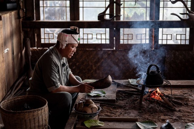  在景迈山芒景村，布朗族茶农南康在火塘边做烤茶（9月14日摄）。